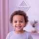 Close-up portrait of a smiling 3-year-old child with diverse ethnicity, looking happy and content.